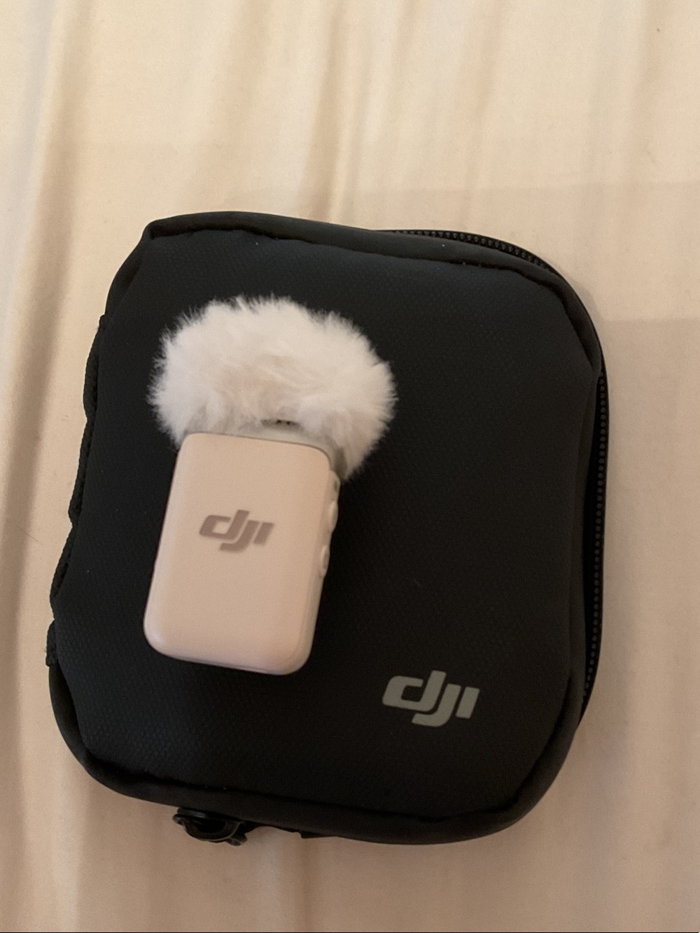 DJI cream wireless lapel microphone with white furry windscreen